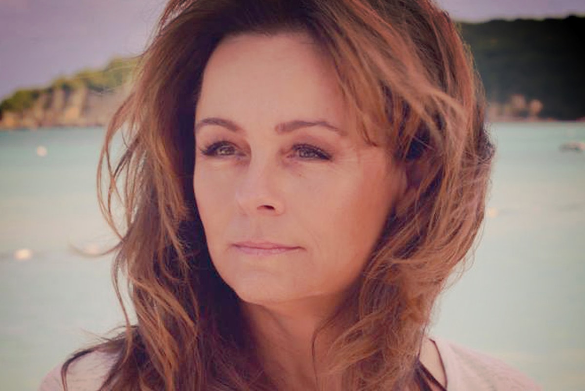 Lisa Thomas with wind-blown hair in front of the water