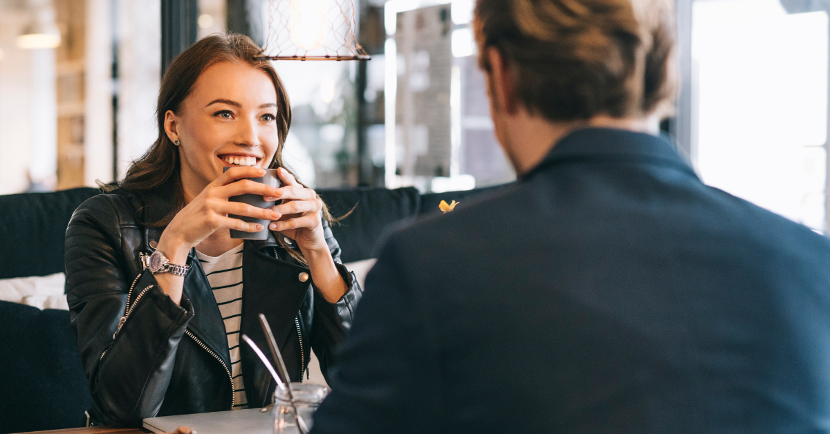 Woman smiling at date across café table, illustrating repeating relationship patterns and attraction to the same type of person