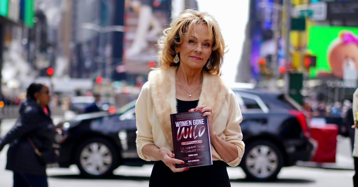 Lisa Thomas holding Women Gone Wild Leadership book, warm natural light, in New York Times Square, confident and present