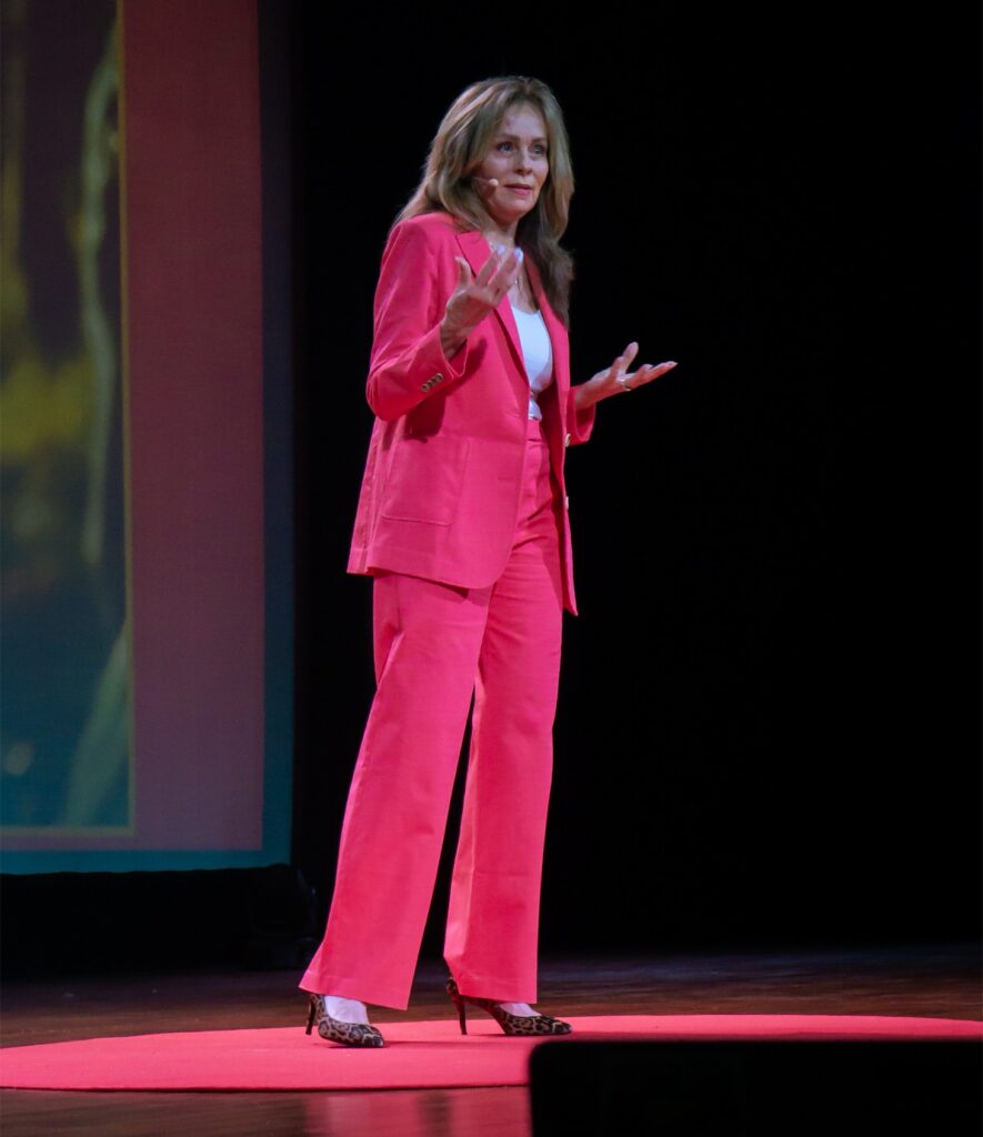 Lisa Thomas speaks on stage at TEDx Ayala Avenue Women, gesturing while wearing a headset microphone.