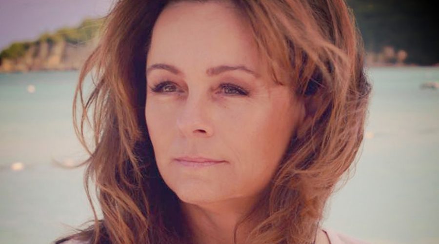 Lisa Thomas with wind-blown hair in front of the water