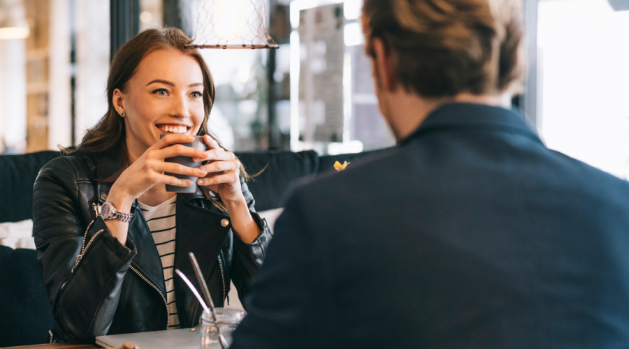 Woman smiling at date across café table, illustrating repeating relationship patterns and attraction to the same type of person