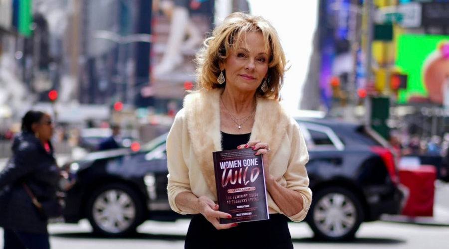 Lisa Thomas holding Women Gone Wild Leadership book, warm natural light, in New York Times Square, confident and present