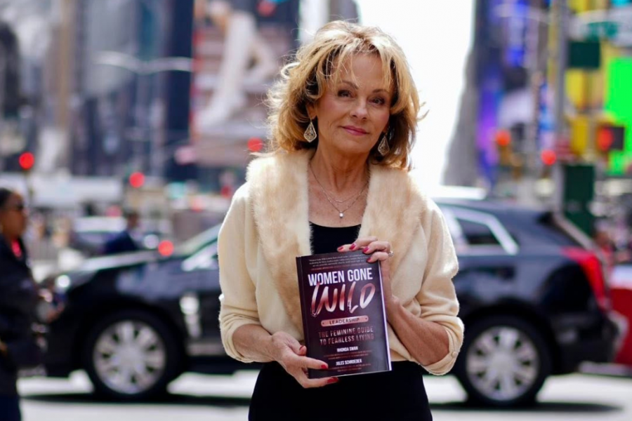 Lisa Thomas holding Women Gone Wild Leadership book, warm natural light, in New York Times Square, confident and present