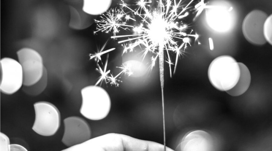 A black and white image of a hand holding a lit sparkler