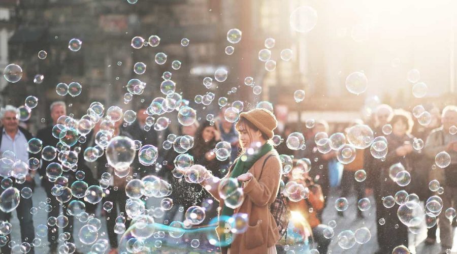 A woman with arms out standing in the middle of a bunch of bubbles